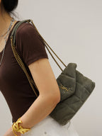 Gray quilted shoulder bag with gold YSL logo on flap and chain strap over arm
