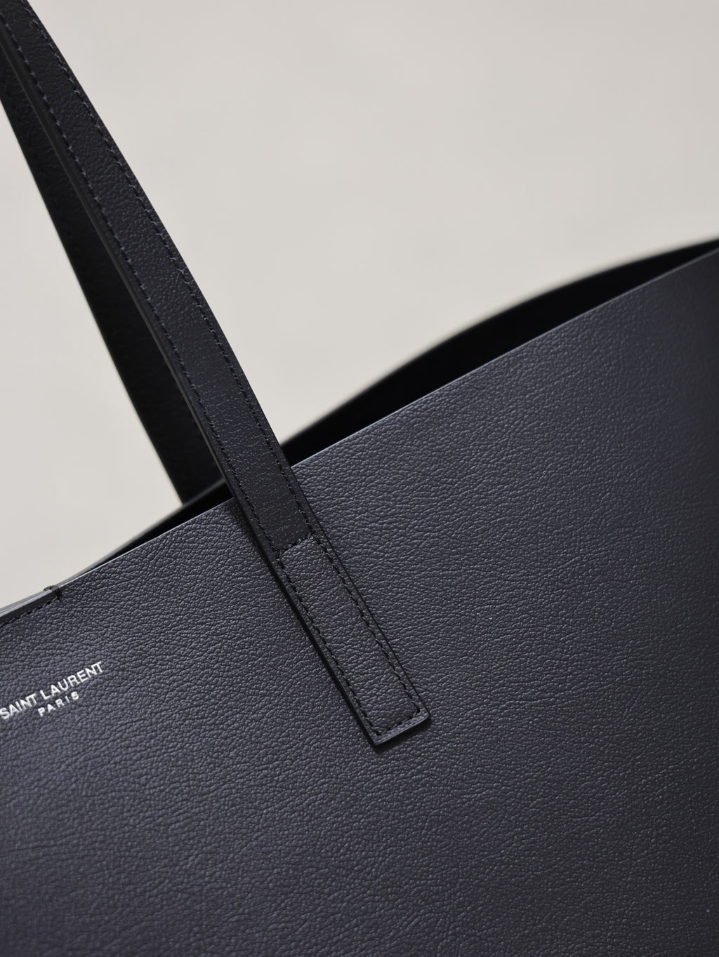Close-up of black leather tote handle strap and textured surface