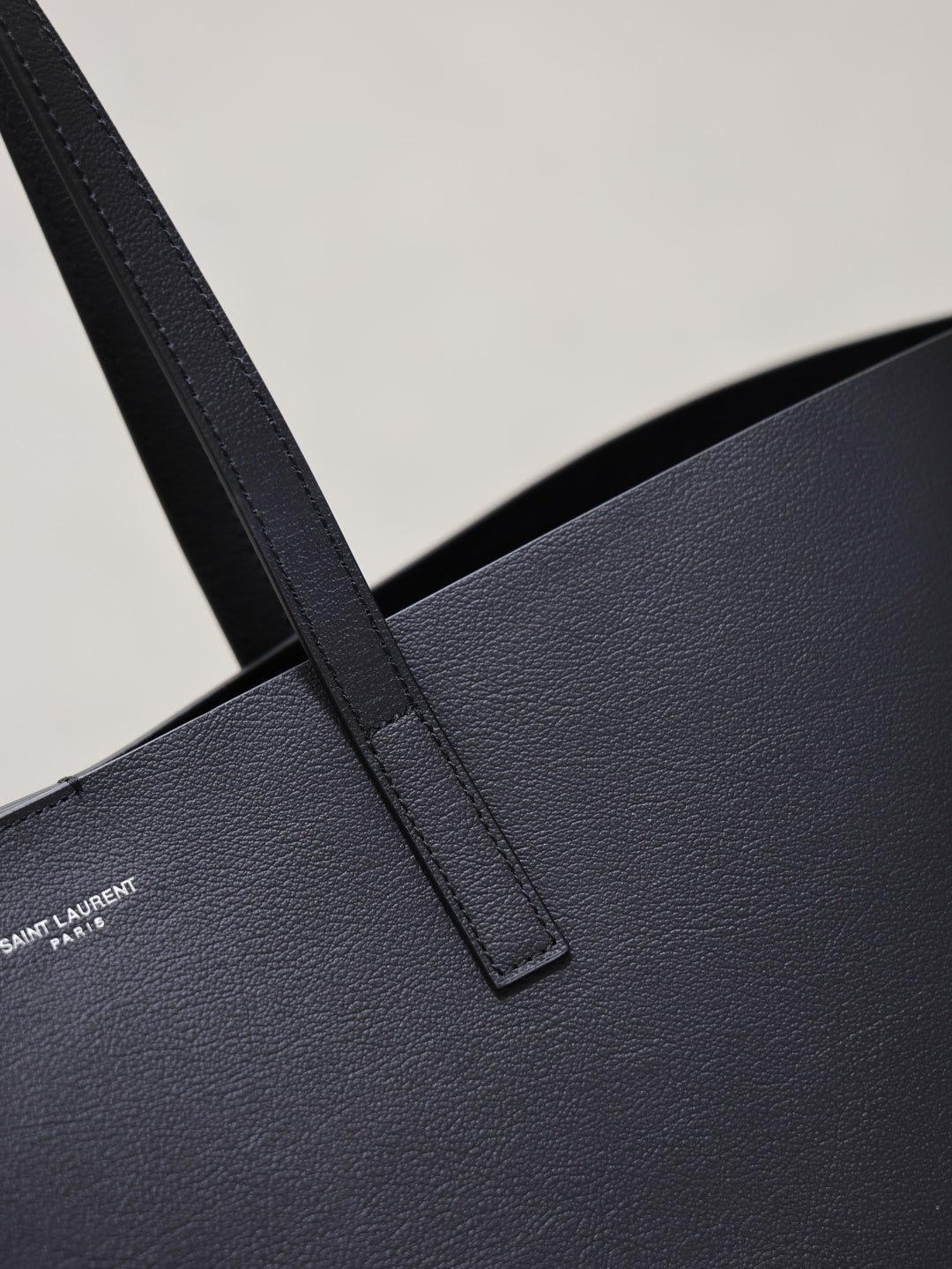 Close-up of black leather tote handle strap and textured surface