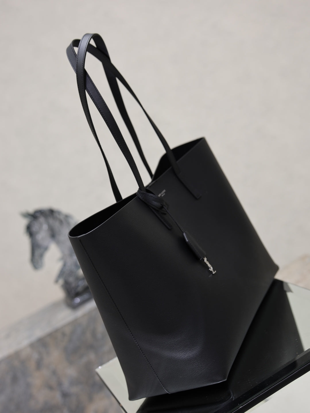 YSL black leather tote bag with top handles and attached hanging charm