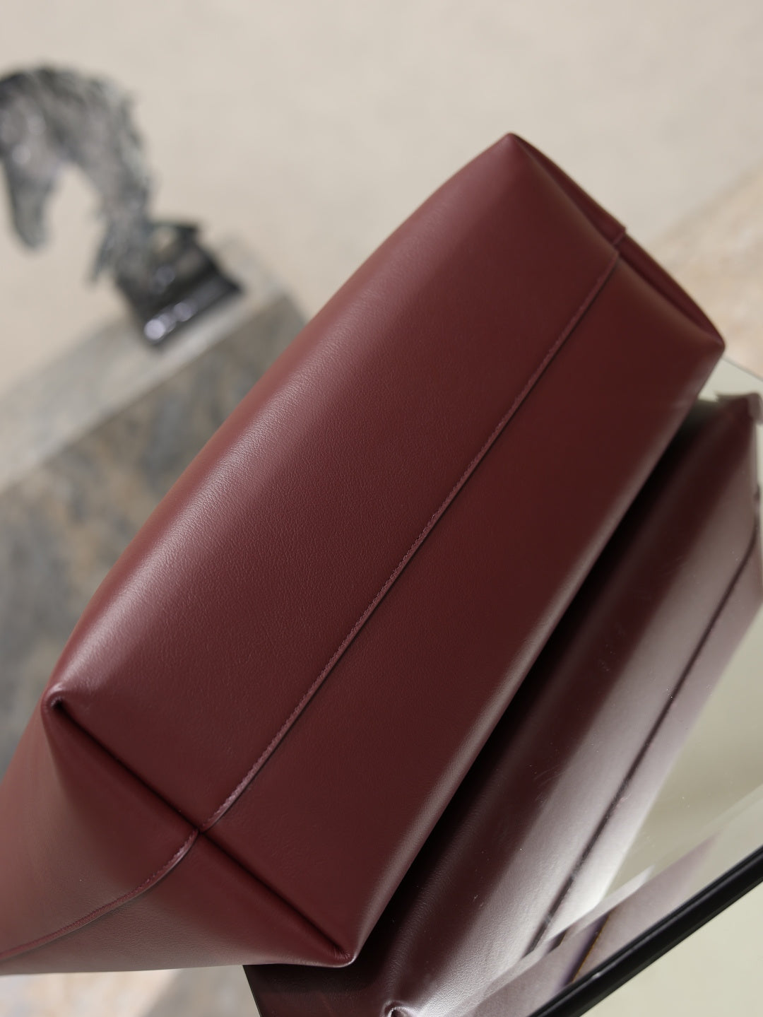 YSL burgundy tote bag close-up of side panel seam on display