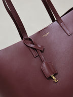 YSL burgundy leather tote bag close-up of front strap and gold-tone charm