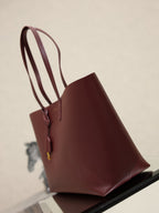 YSL burgundy tote bag side view on display with structured silhouette
