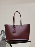 YSL burgundy tote bag with top handles and dangling gold-tone logo charm
