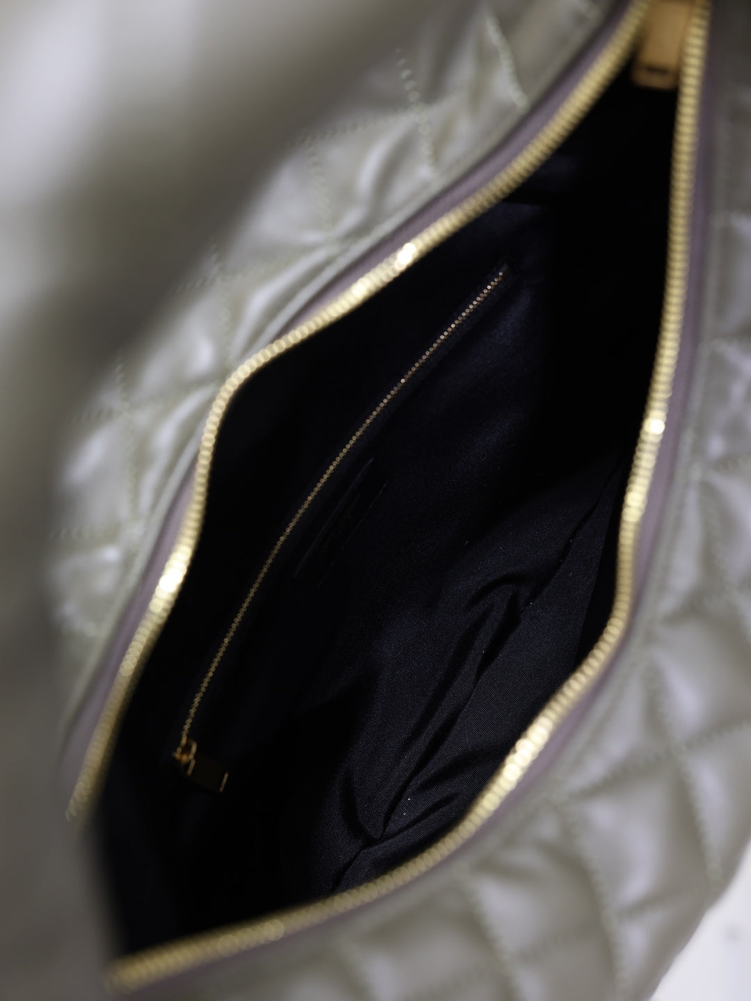 Inside view of quilted hobo bag with black lining and zippered pocket