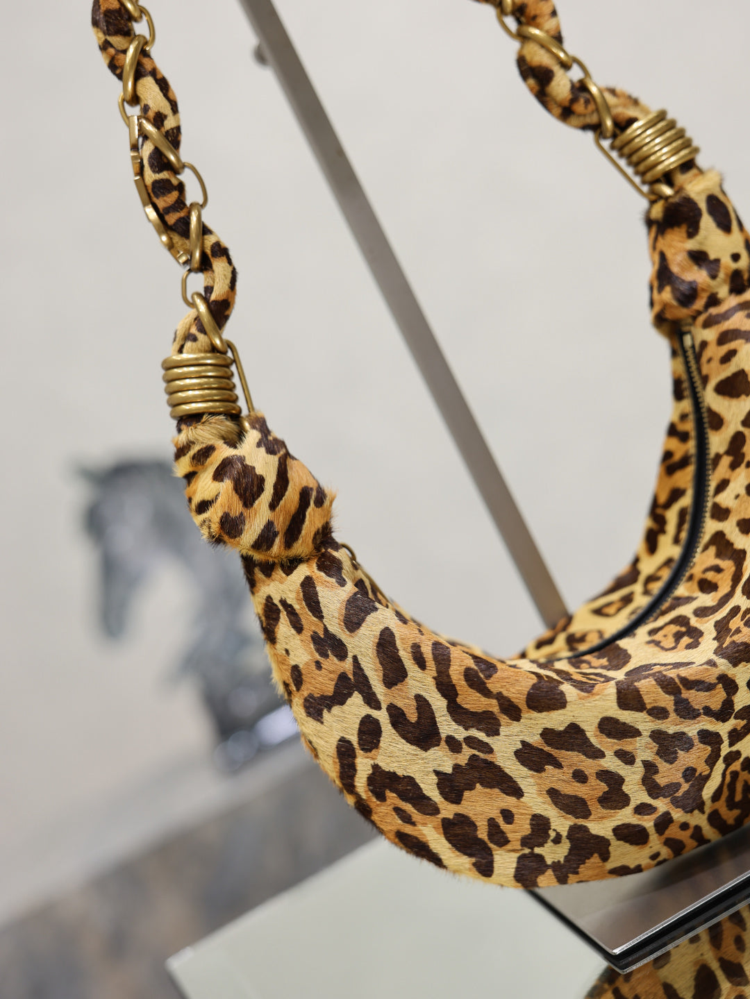 YSL bag close-up, leopard-print fabric with braided chain strap and curved top opening