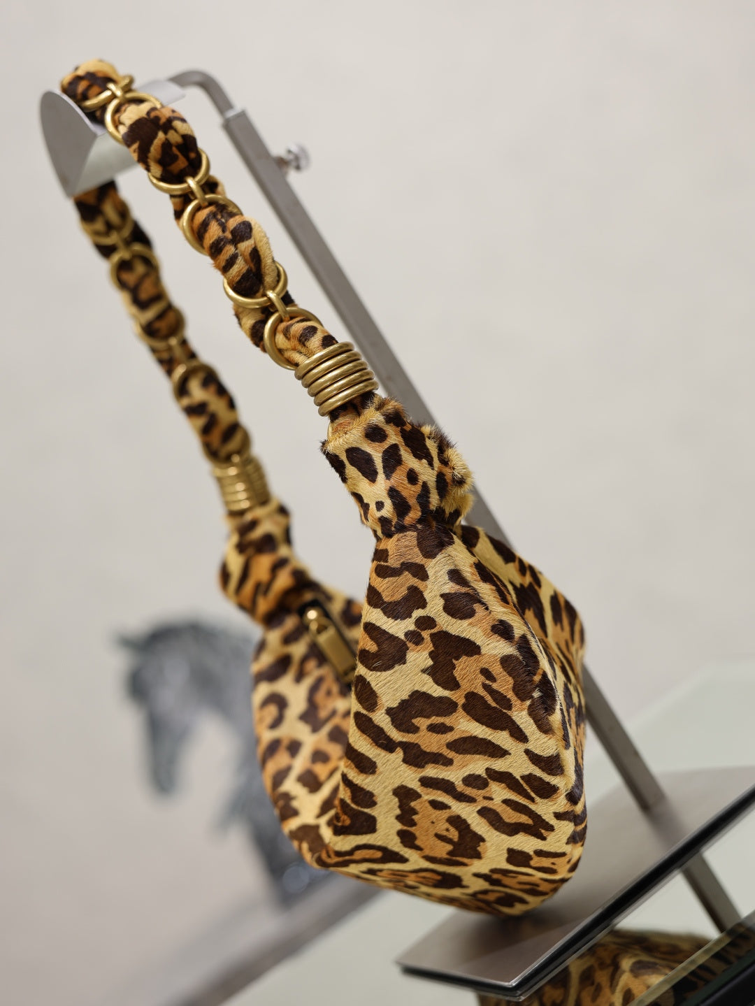 YSL bag side view, leopard-print hobo bag with braided chain strap and ribbed gold details