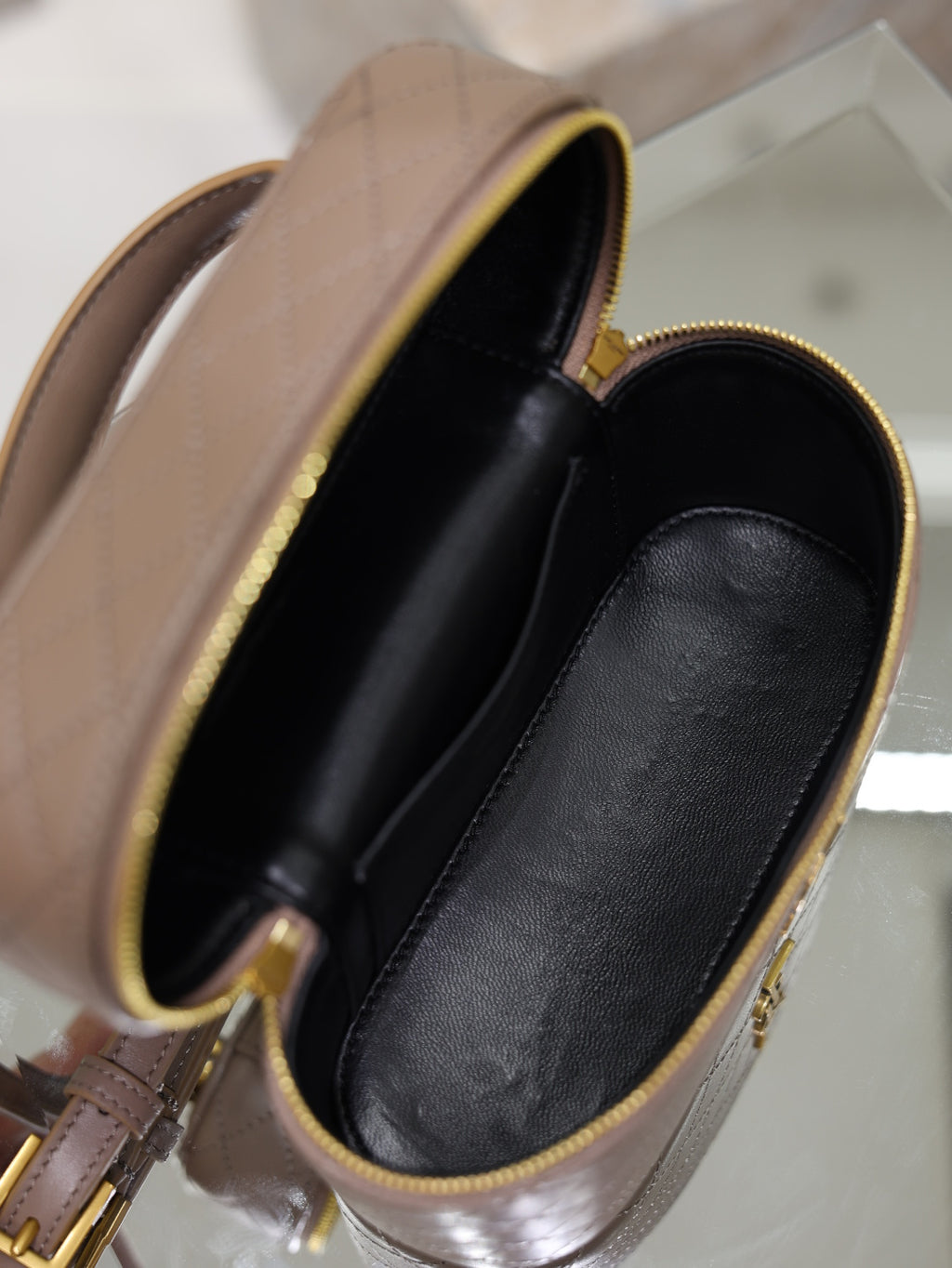 Taupe mini bag interior view with black-lined pocket and gold-tone hardware.