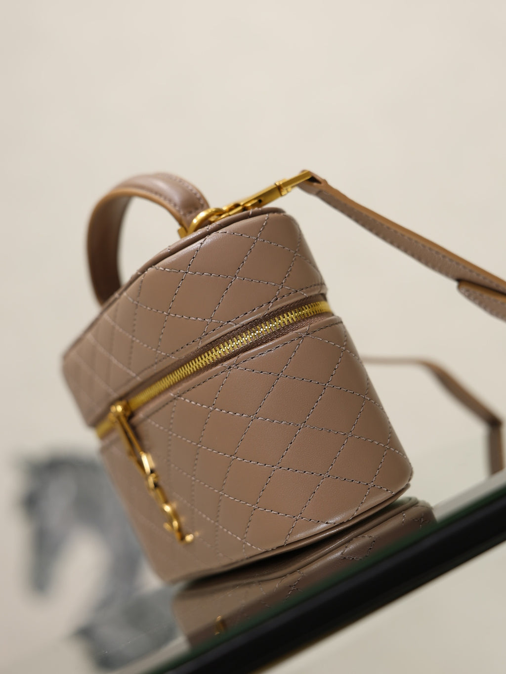 Taupe quilted mini bag side view with top handle and gold-tone zip.
