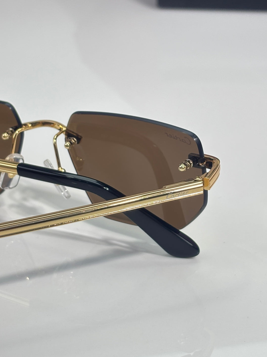 Cartier glasses close-up of gold bridge, dark arms, and brown tinted lens