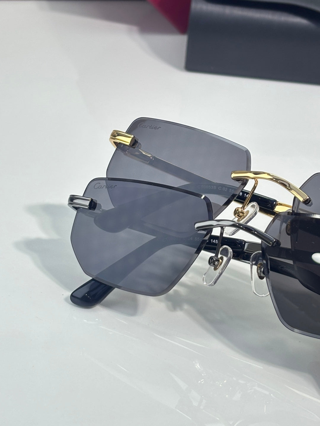 Cartier glasses on display, showing stacked frames with dark arms and gray tinted lenses