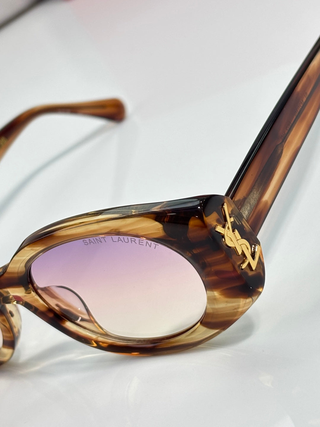 Tortoiseshell cat-eye sunglasses close-up with gold YSL emblem on temple