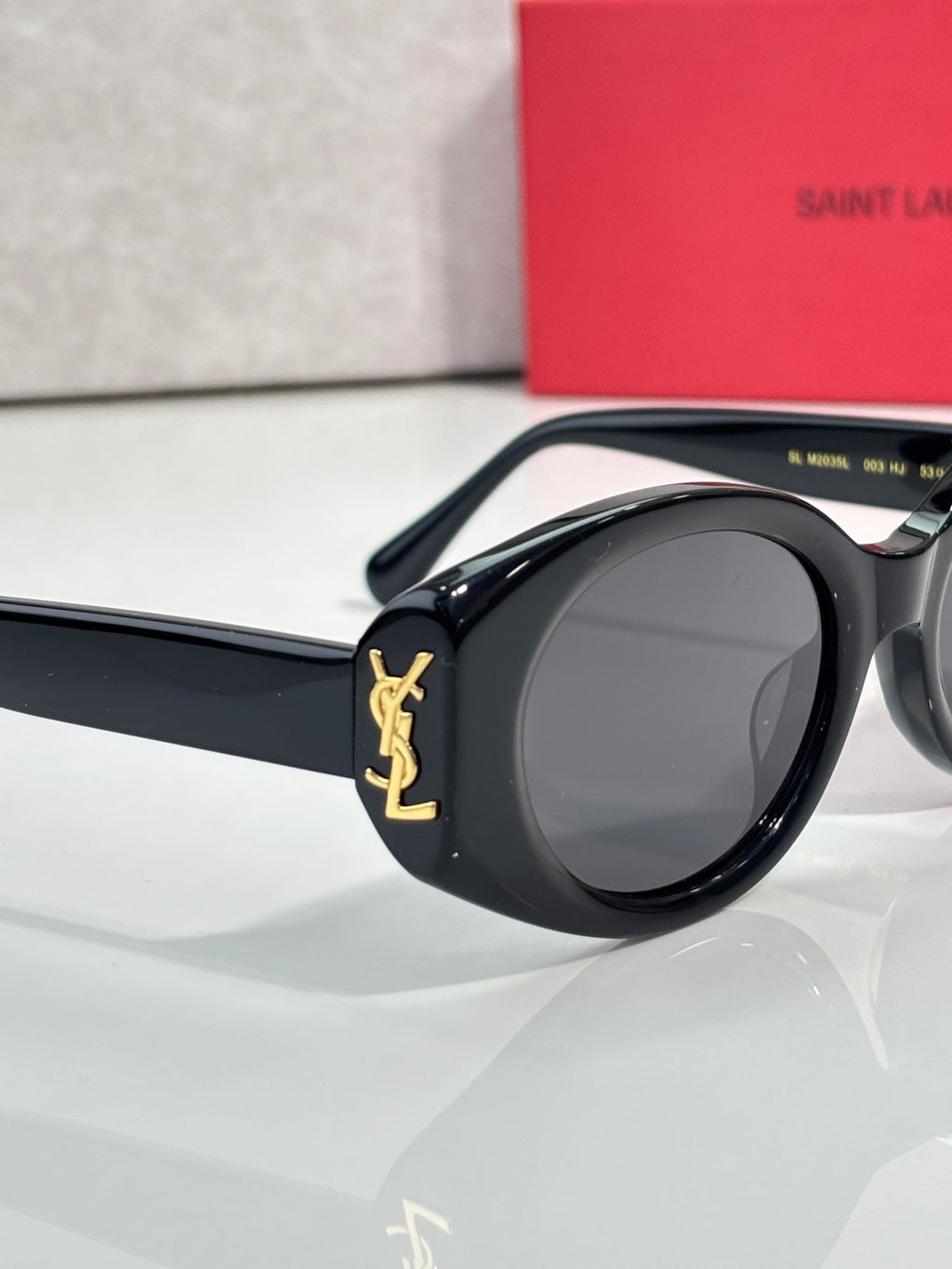 Black cat-eye sunglasses with dark lenses and gold YSL emblem on the arm