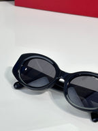 Cat-eye sunglasses with dark lenses and glossy black frames, angled side view
