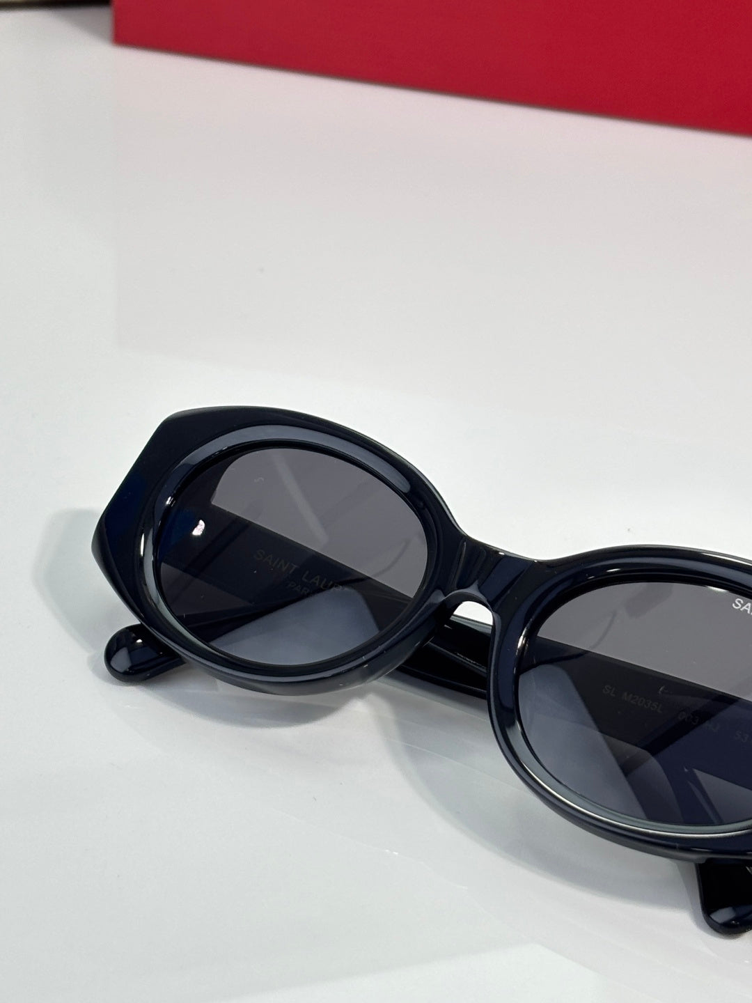 Cat-eye sunglasses with dark lenses and glossy black frames, angled side view