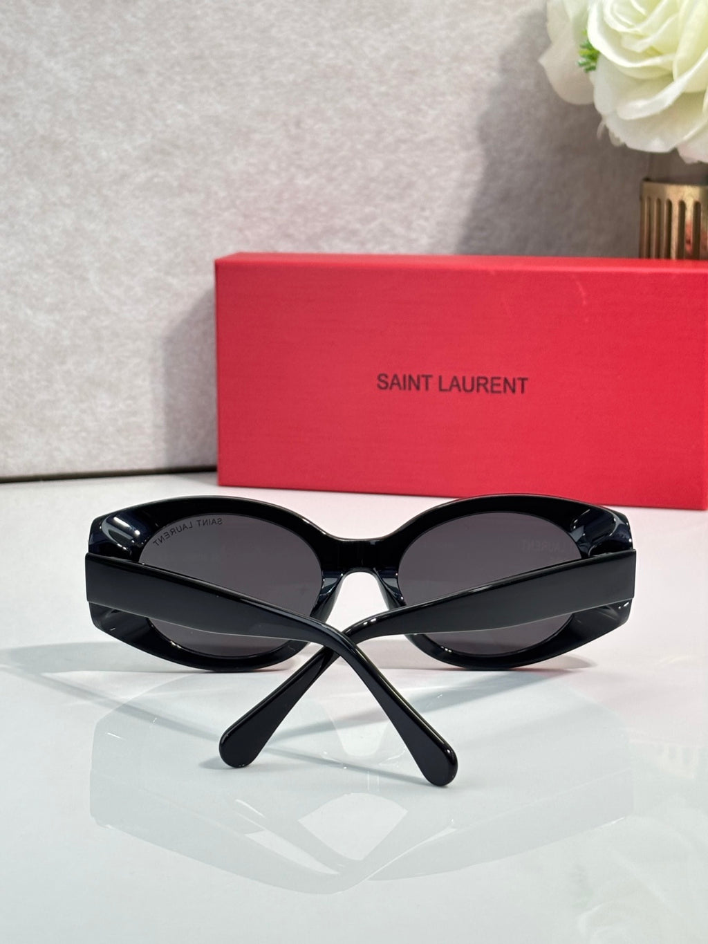 Cat-eye sunglasses with black frames and dark lenses, gold logo detail