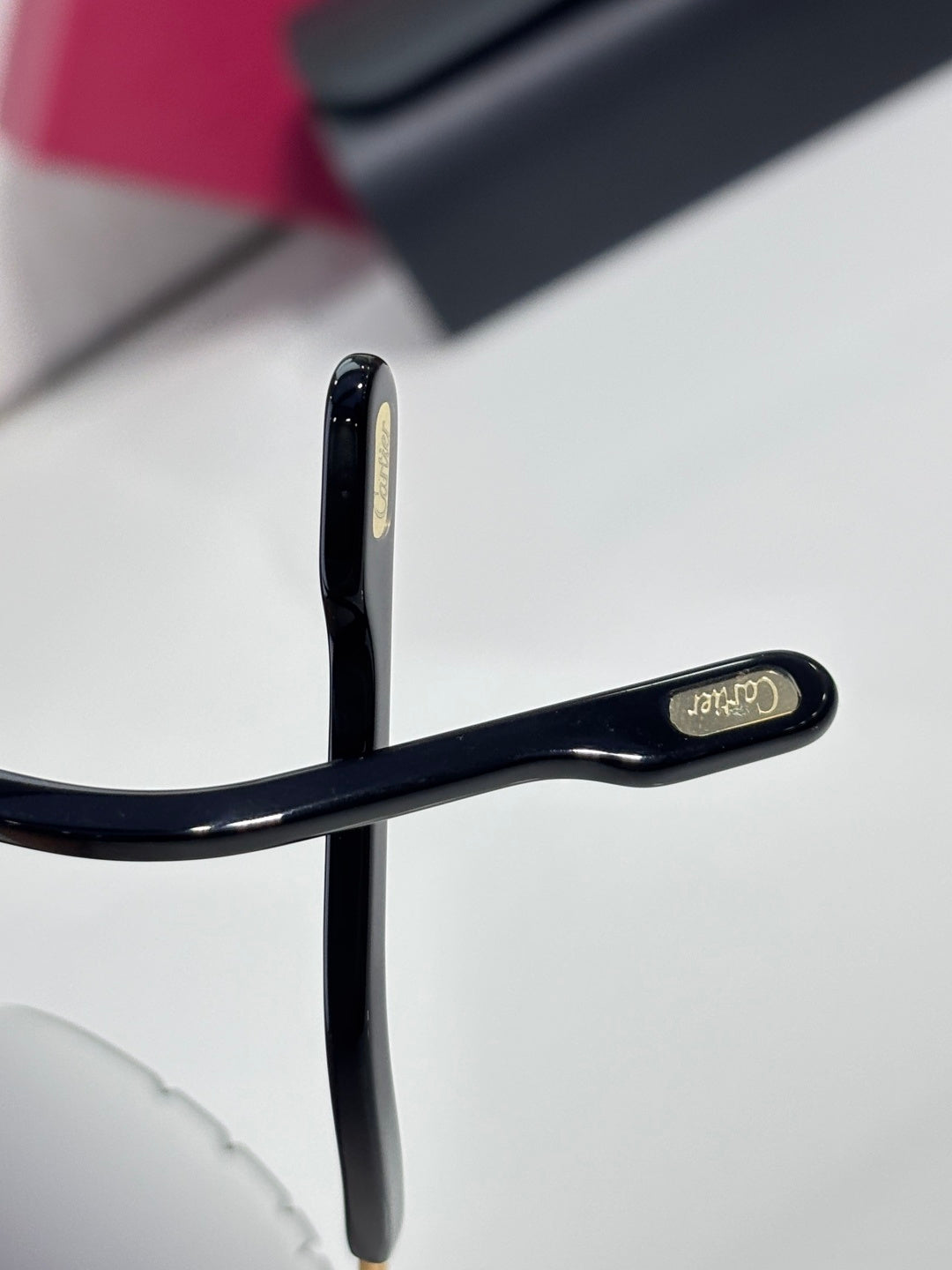 Close-up of dark eyeglasses temple with gold-tone logo plate