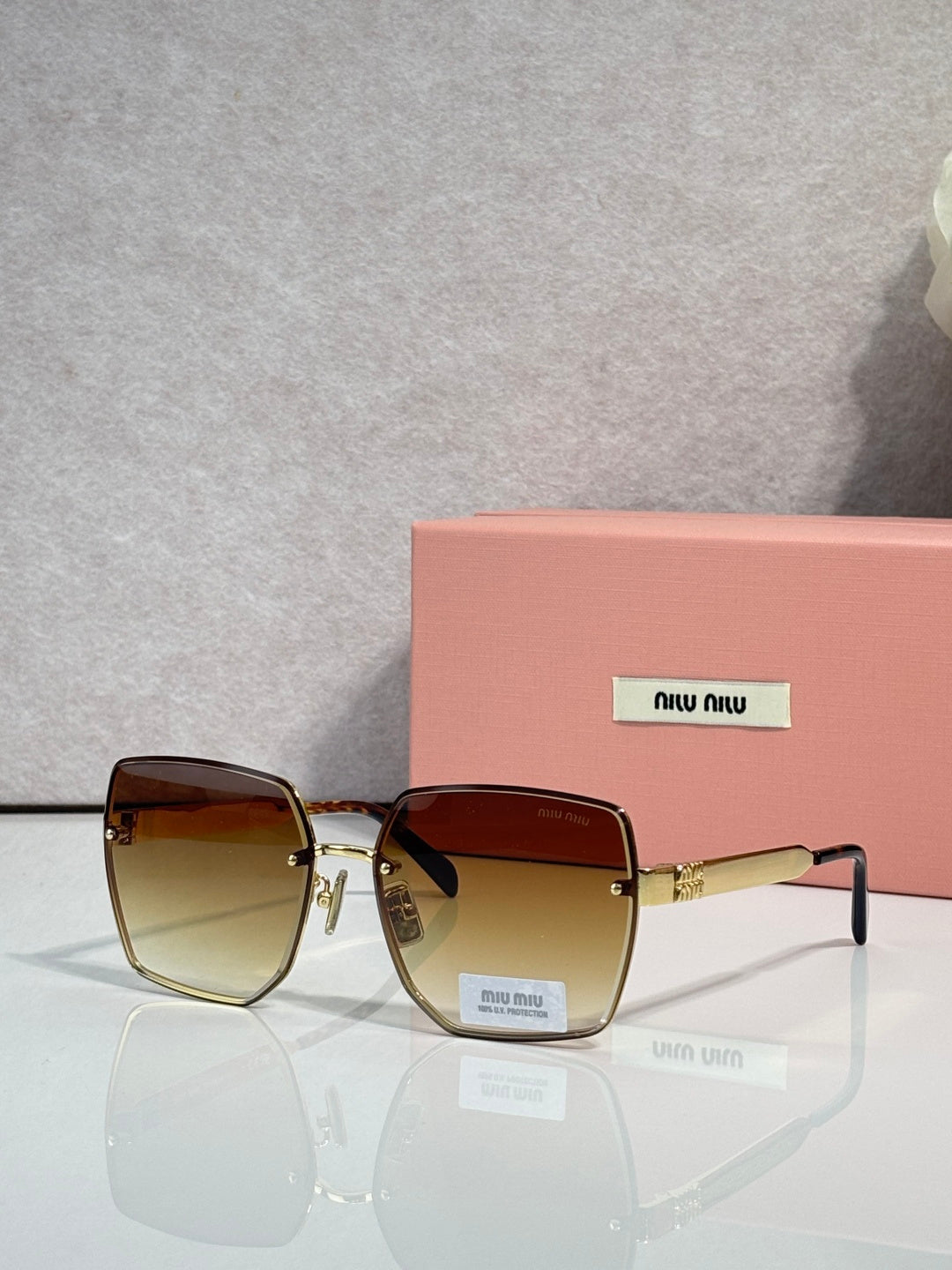 MiuMiu square gold glasses with amber-to-clear gradient lenses and metal hinges