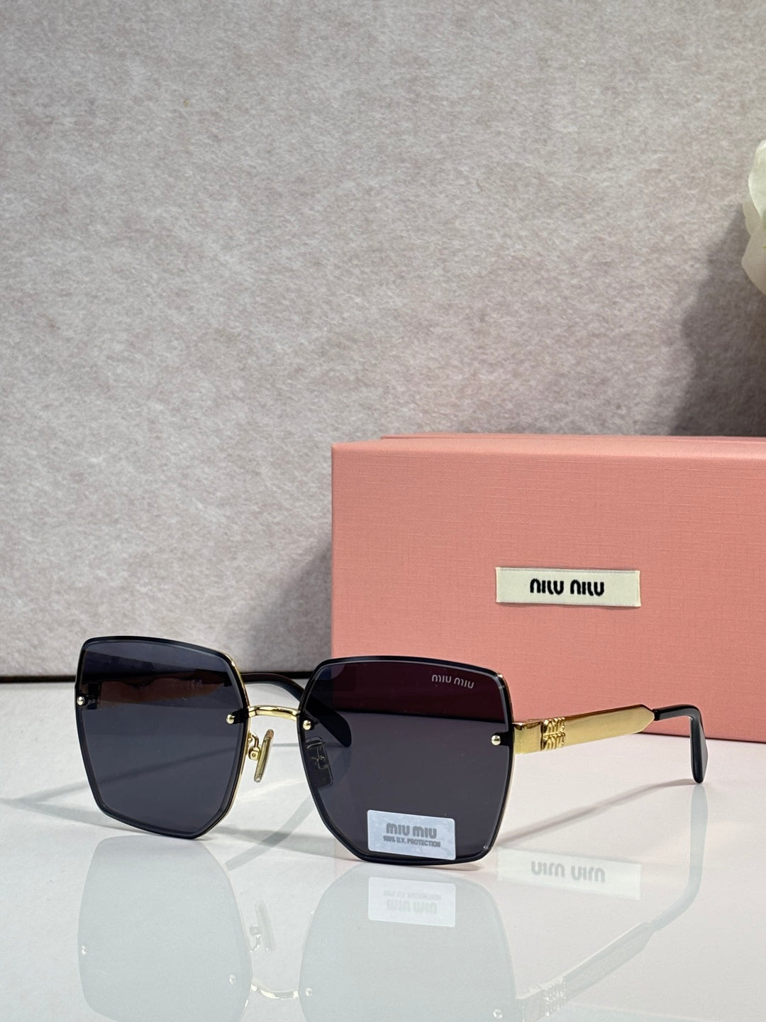 MiuMiu square black glasses with dark tinted lenses and gold-tone hinges