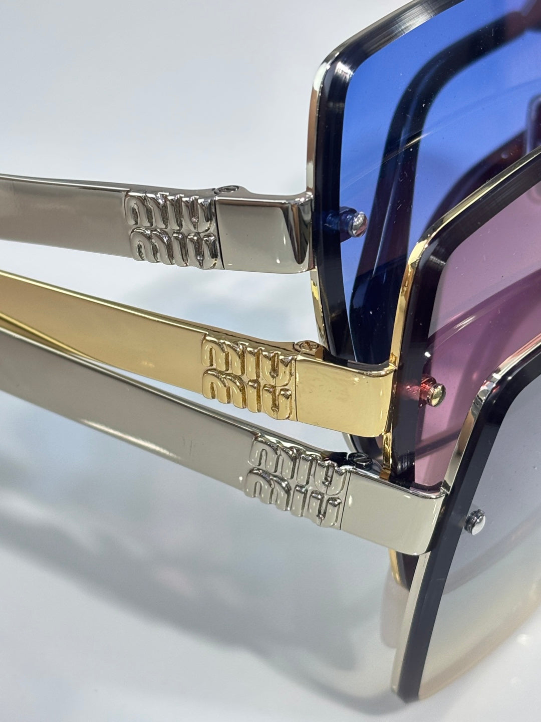 MiuMiu glasses close-up of gold and blue hinge with engraved metal details