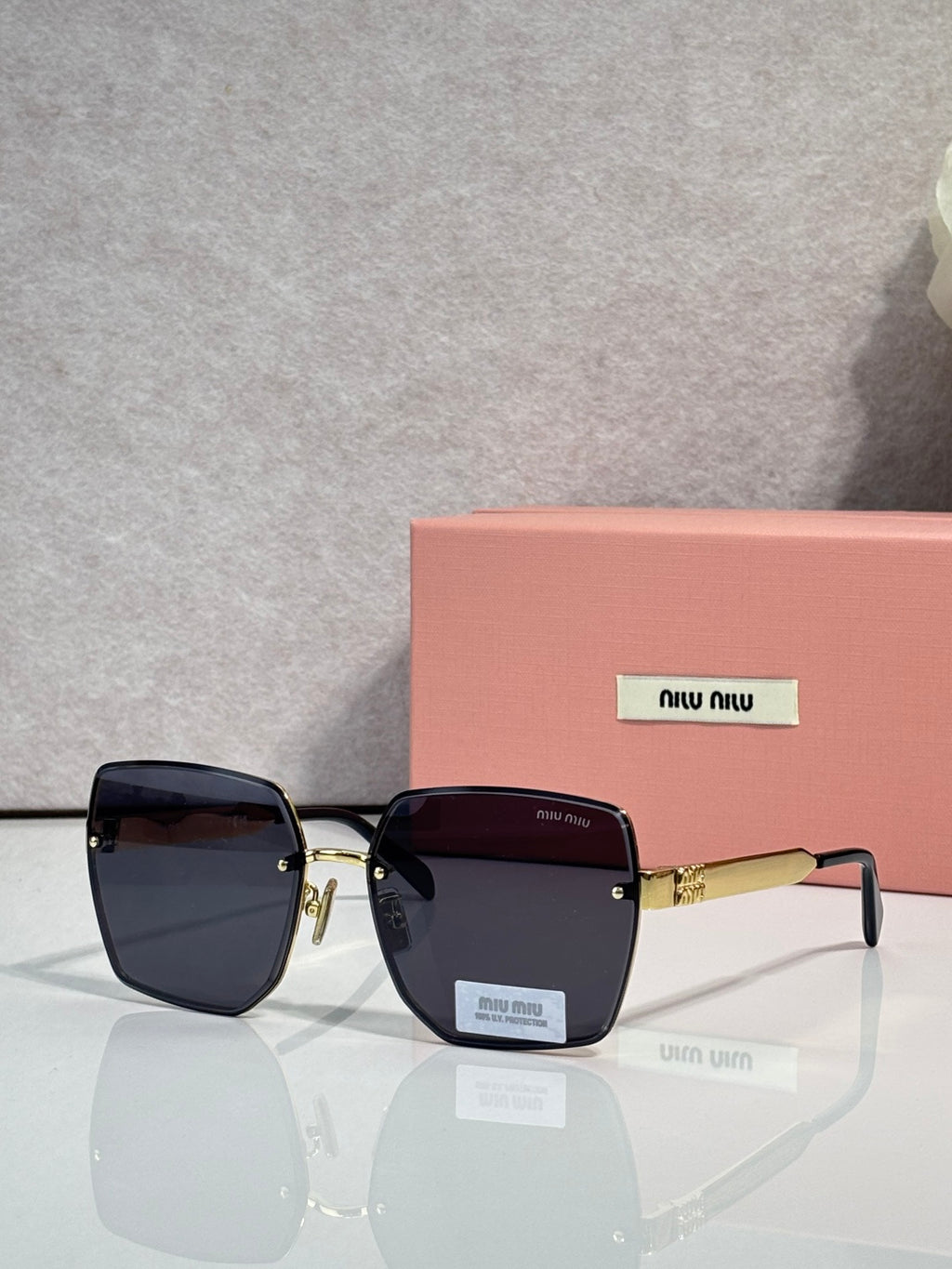 MiuMiu rectangular black glasses with dark gradient lenses and gold-tone arms
