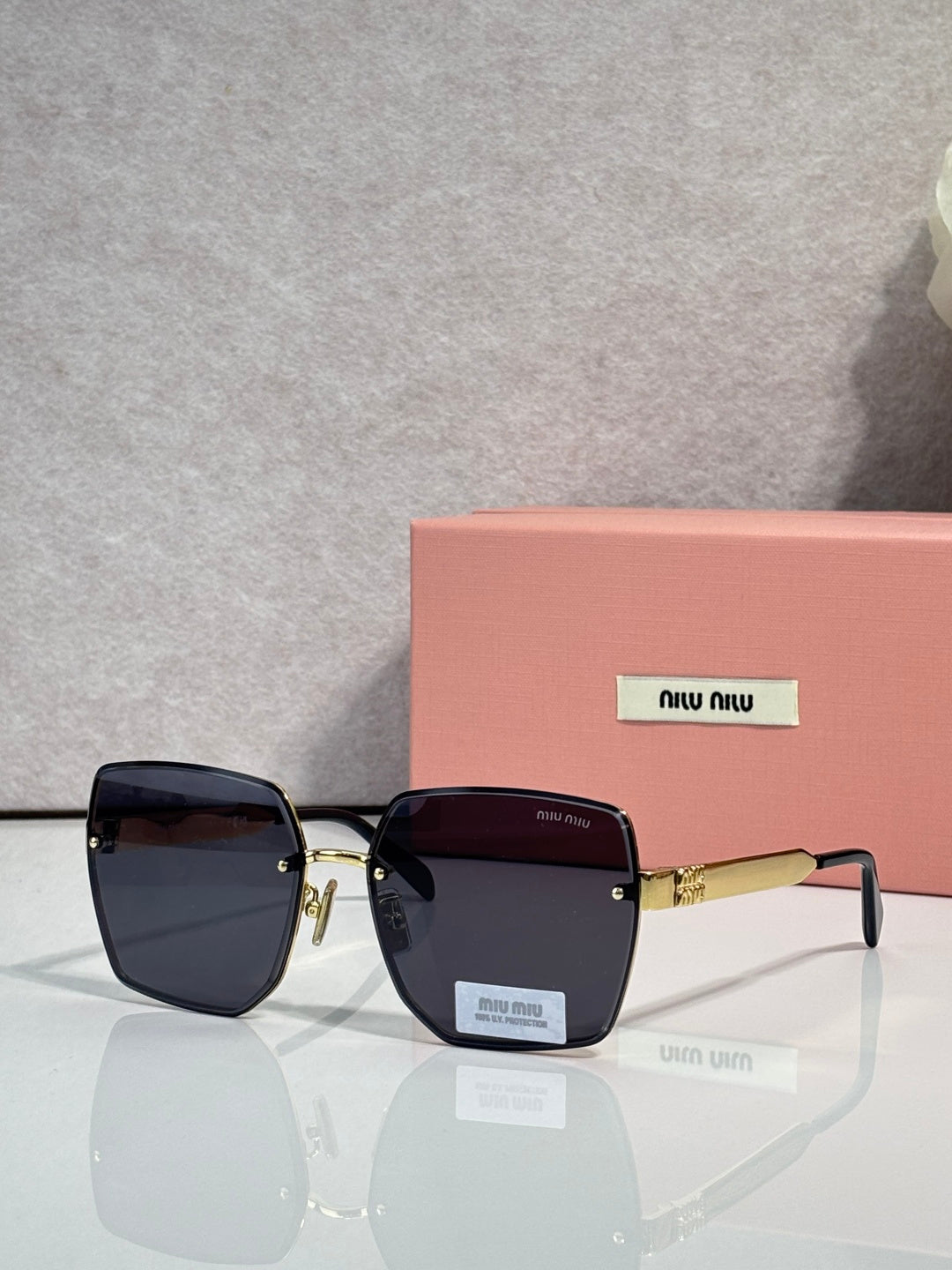 MiuMiu rectangular black glasses with dark gradient lenses and gold-tone arms