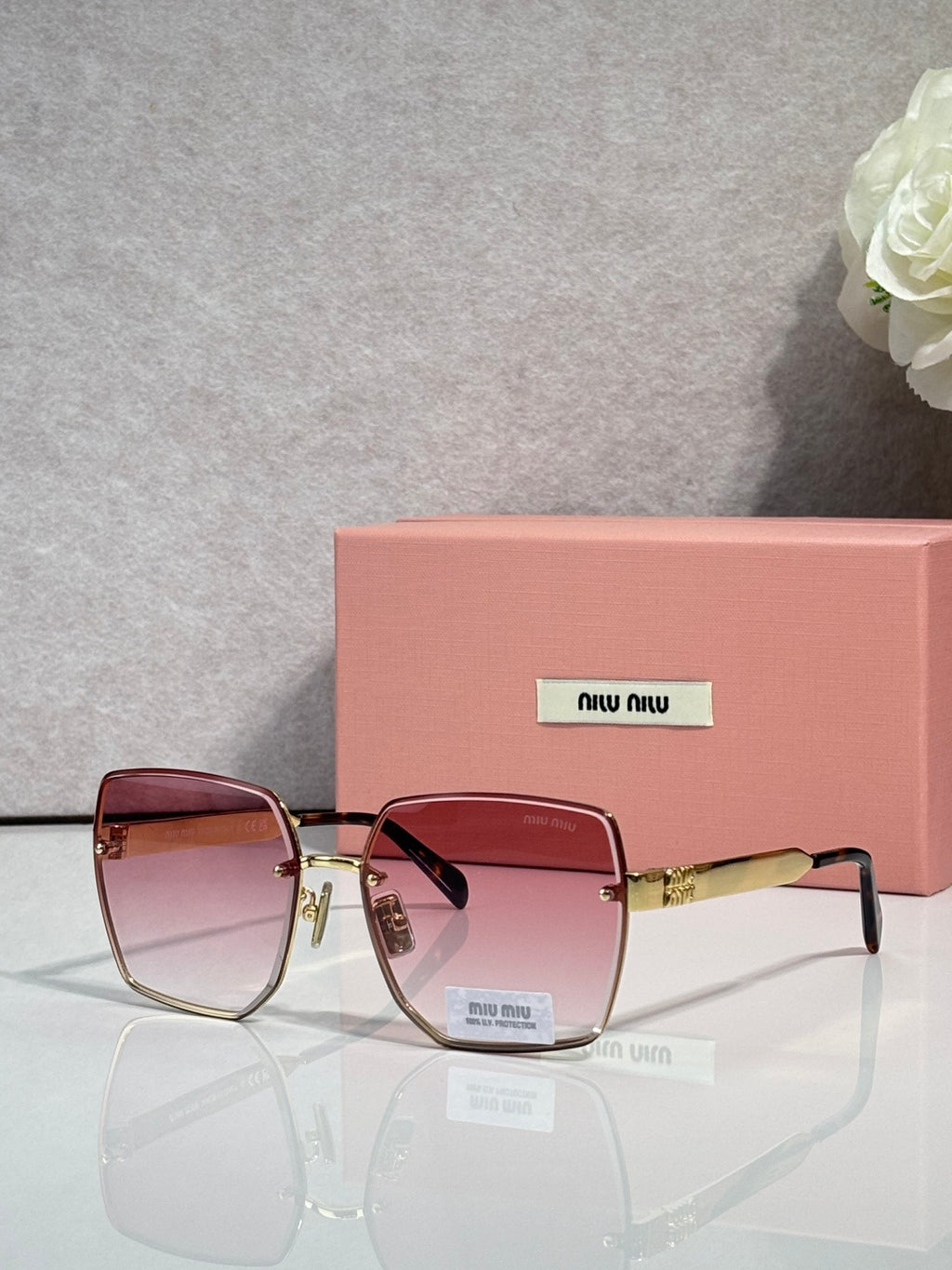 MiuMiu square gold glasses with reddish gradient lenses and gold-tone temples
