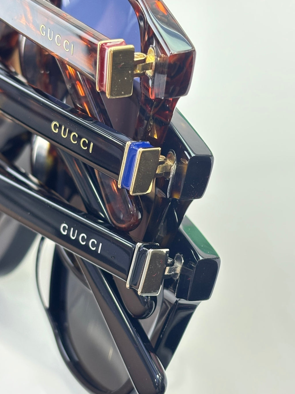 Gucci sunglasses close-up, tortoiseshell frame with gold-tone hinge and Gucci logo