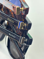 Gucci sunglasses close-up, tortoiseshell frame with gold-tone hinge and Gucci logo