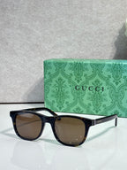 Gucci sunglasses with brown lenses and black acetate frame, gold logo on temple