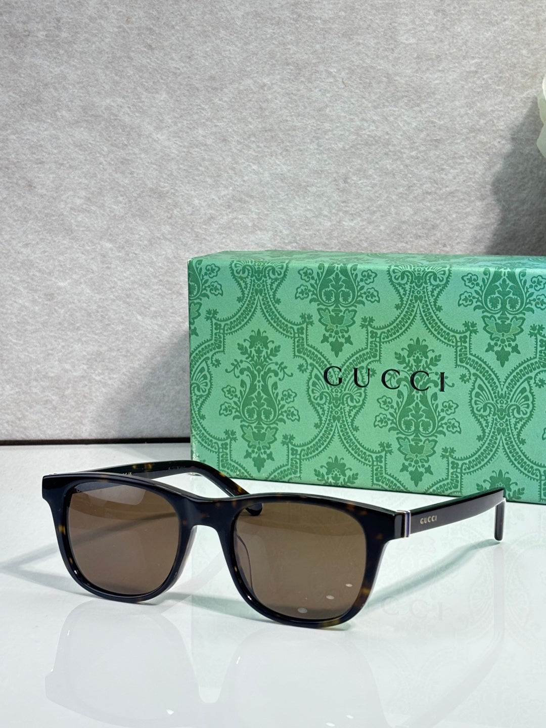 Gucci sunglasses with brown lenses and black acetate frame, gold logo on temple