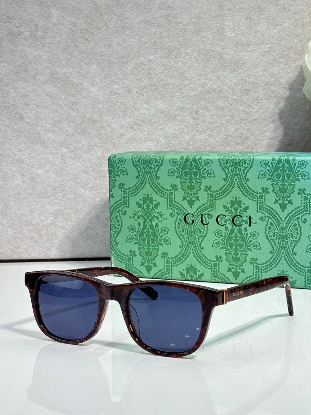 Gucci sunglasses with dark blue lenses and tortoiseshell frame, gold logo on temple