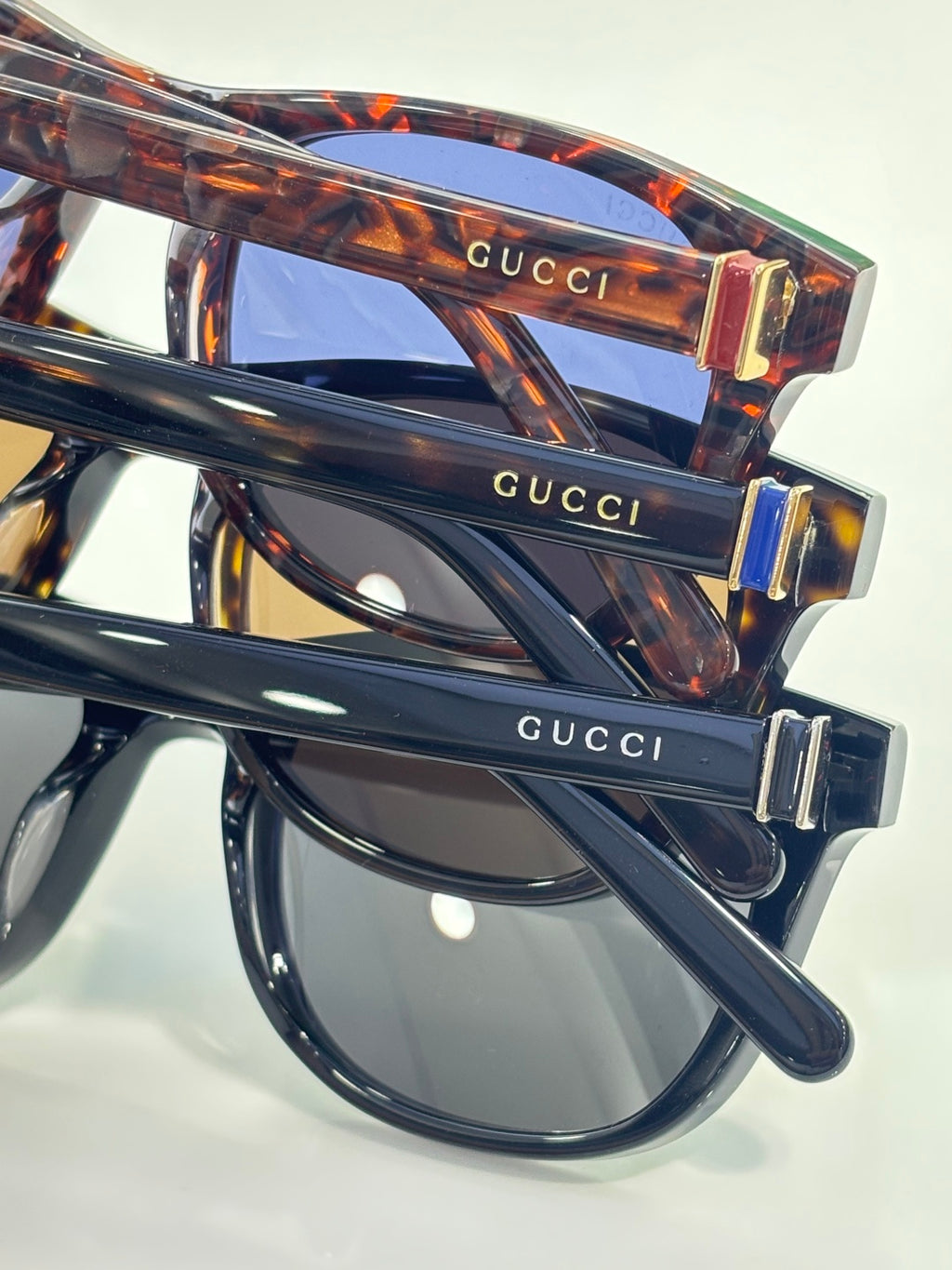Gucci sunglasses close-up, tortoiseshell temple with gold-tone hinge and logo