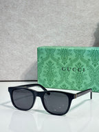 Gucci sunglasses with dark lenses and black acetate frame, gold logo on temple