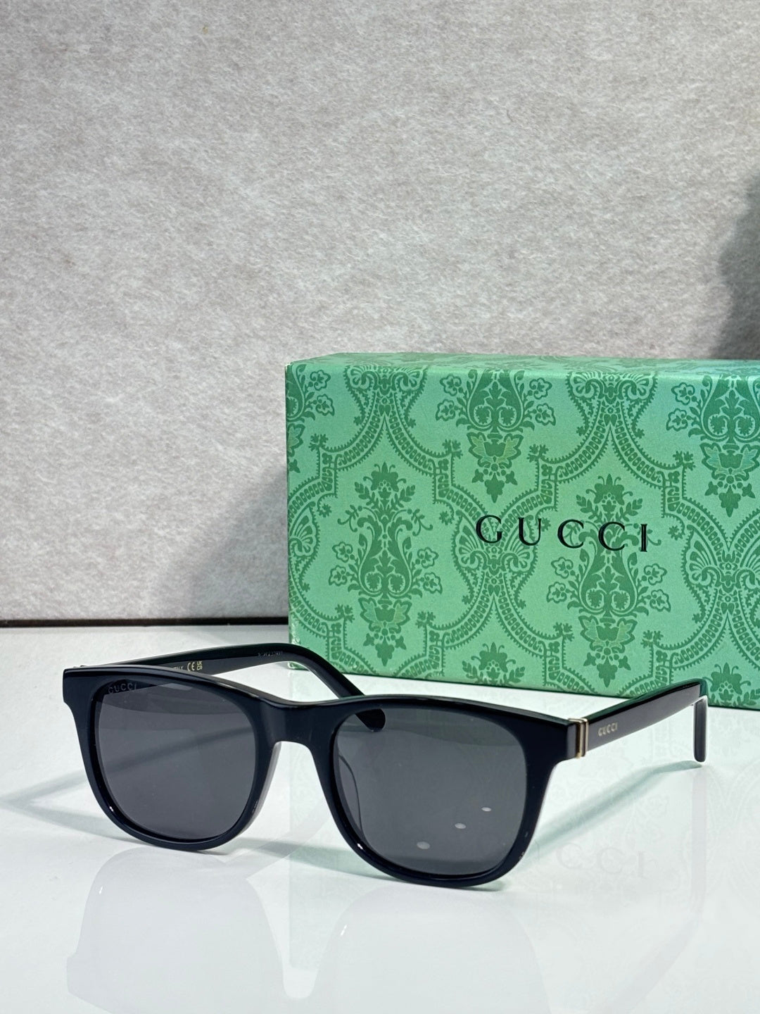Gucci sunglasses with dark lenses and black acetate frame, gold logo on temple