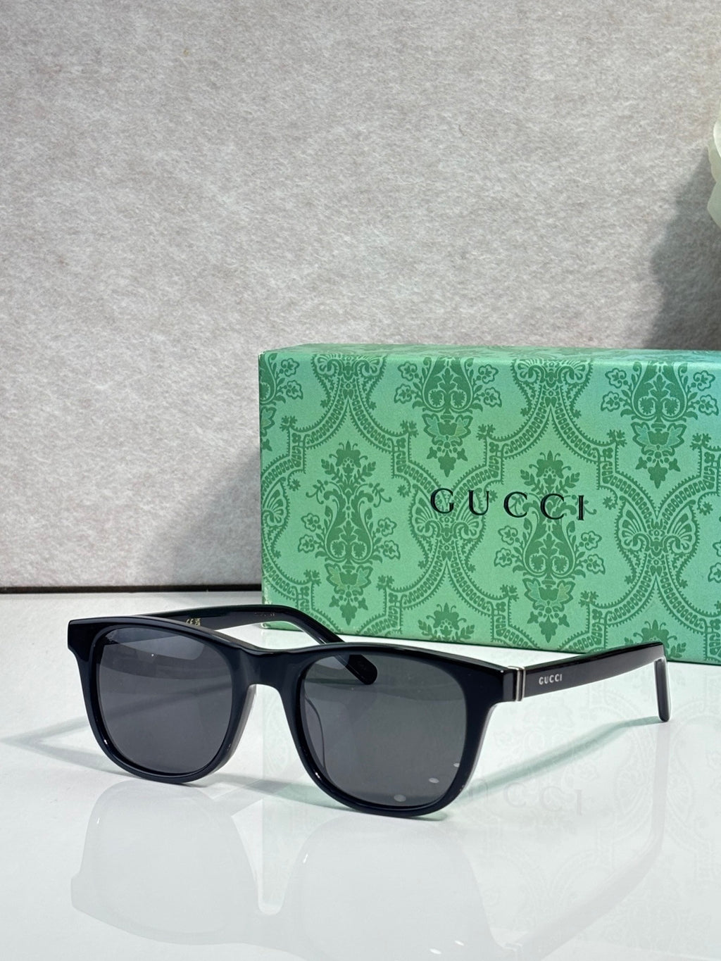 Gucci sunglasses with dark lenses and black acetate frame, rectangular style, gold logo