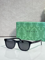 Gucci sunglasses with dark lenses and black acetate frame, rectangular style, gold logo