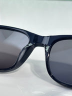 Gucci sunglasses close-up, glossy dark frame with smoke-tinted lenses