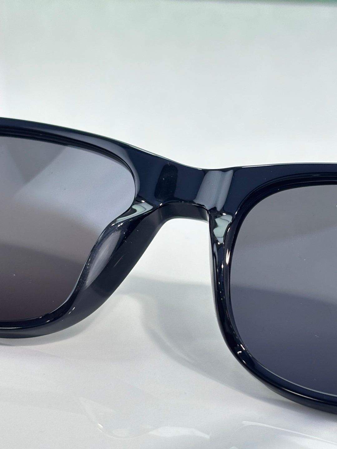 Gucci sunglasses close-up, glossy dark frame with smoke-tinted lenses