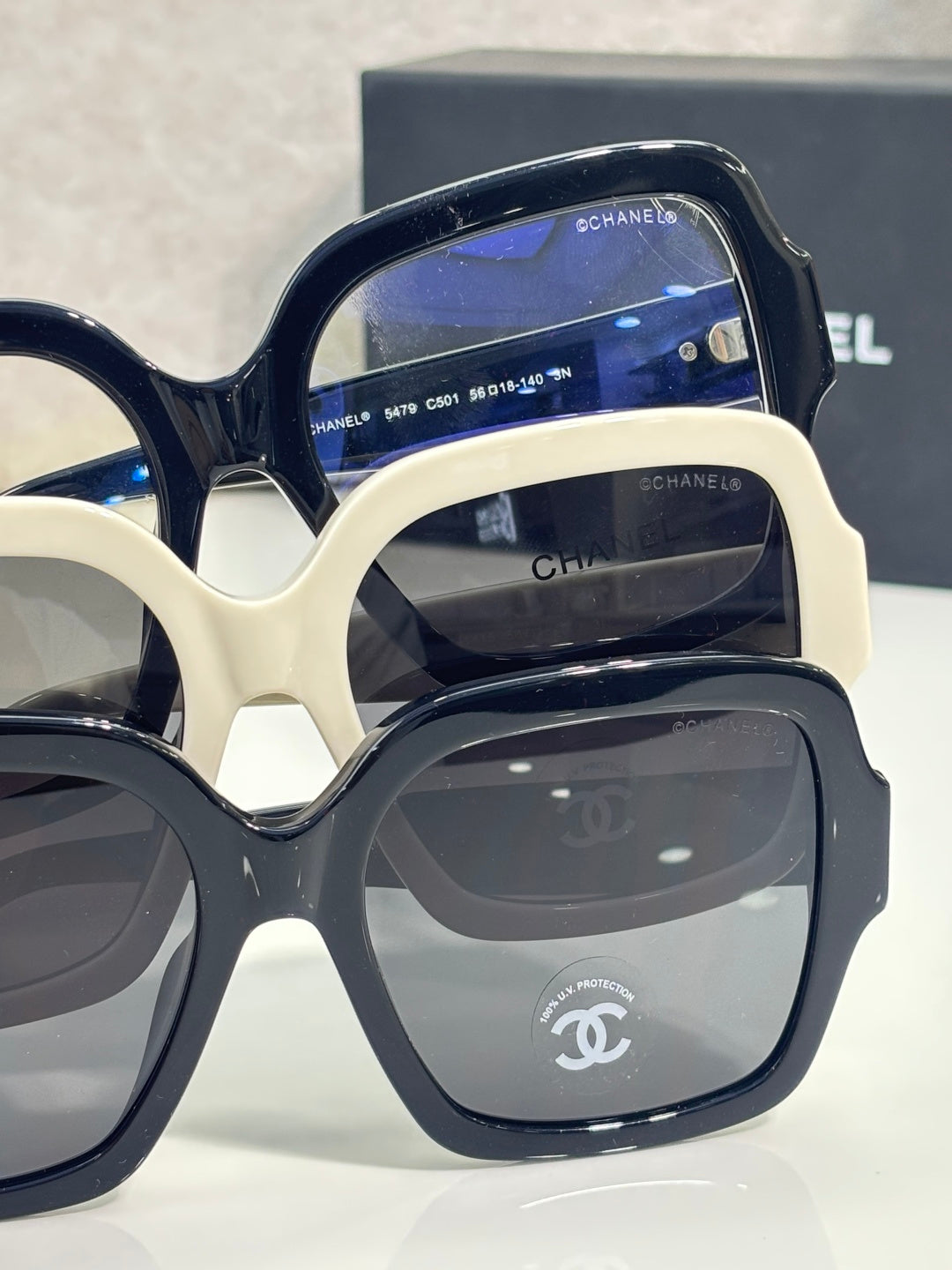 Stacked square acetate sunglasses, navy and white frames with dark lenses