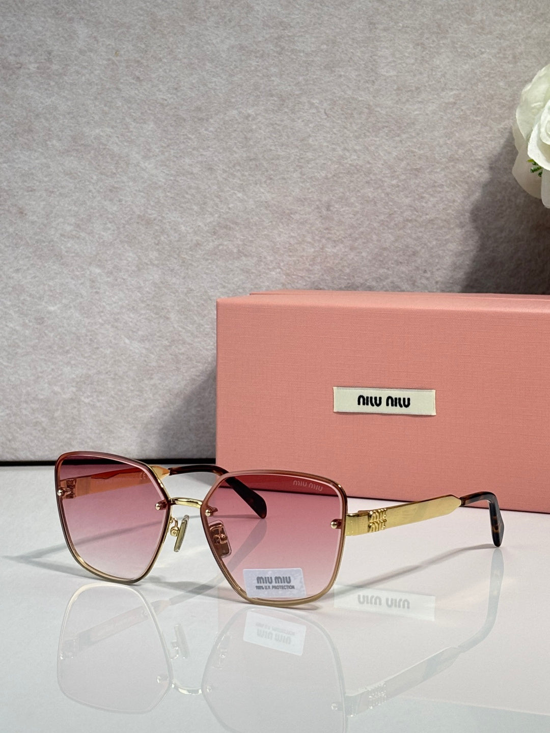 Sunglasses with rose lenses, burgundy frame, and gold-tone temple detailing