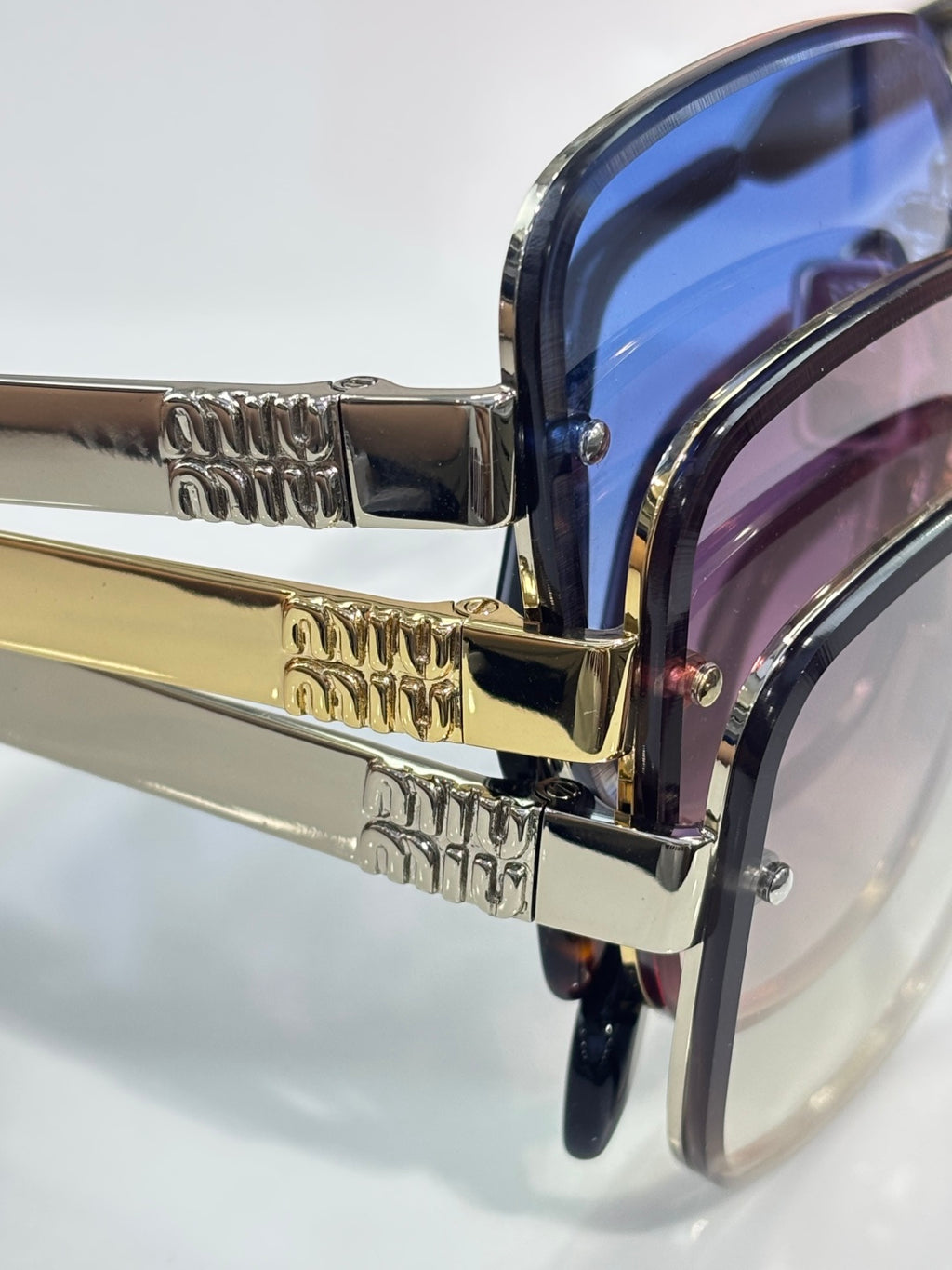Sunglasses close-up: blue-tinted lens frame edge with gold metal hinge