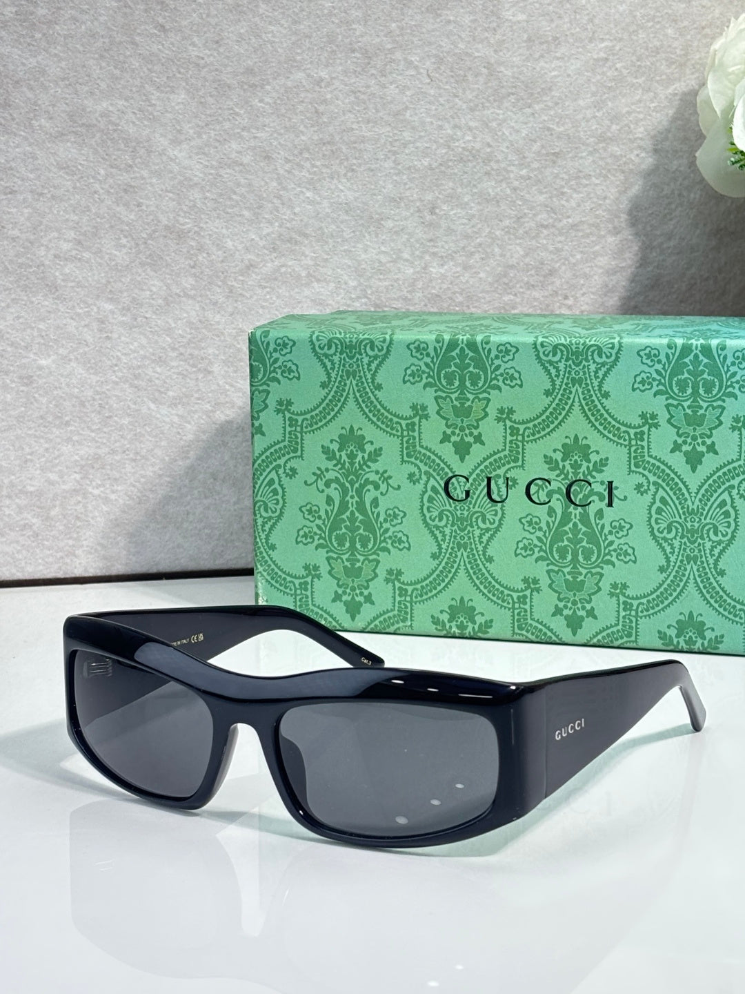 Black cat-eye eyeglasses with dark gray lenses and gold-tone logo on side
