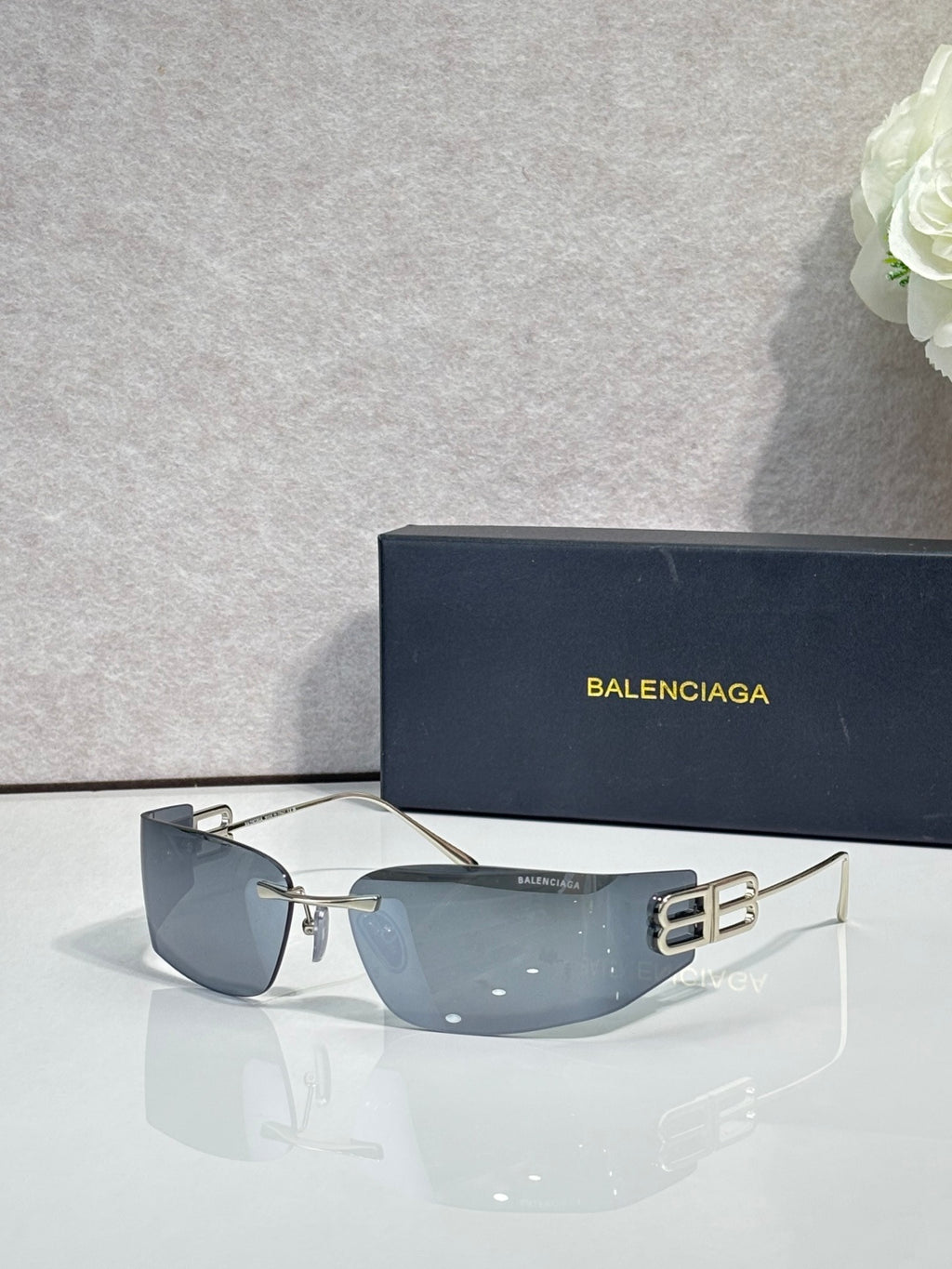 Balenciaga sunglasses with dark blue gradient lenses and black frame, gold logo on arms