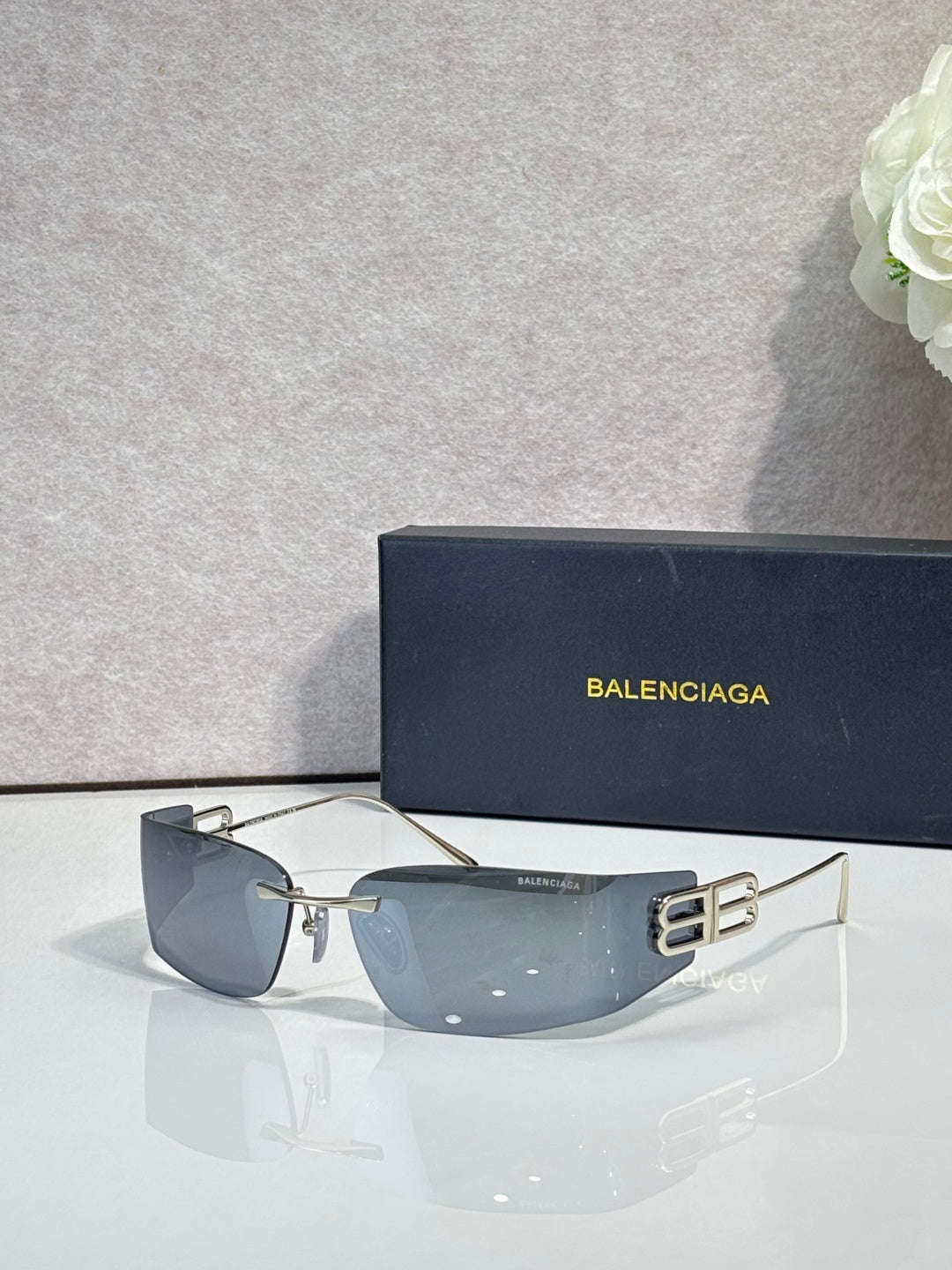 Balenciaga sunglasses with dark blue gradient lenses and black frame, gold logo on arms