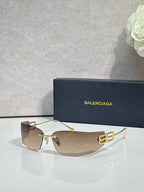Balenciaga sunglasses with clear-to-light brown lenses and gold-tone frame, logo side detail