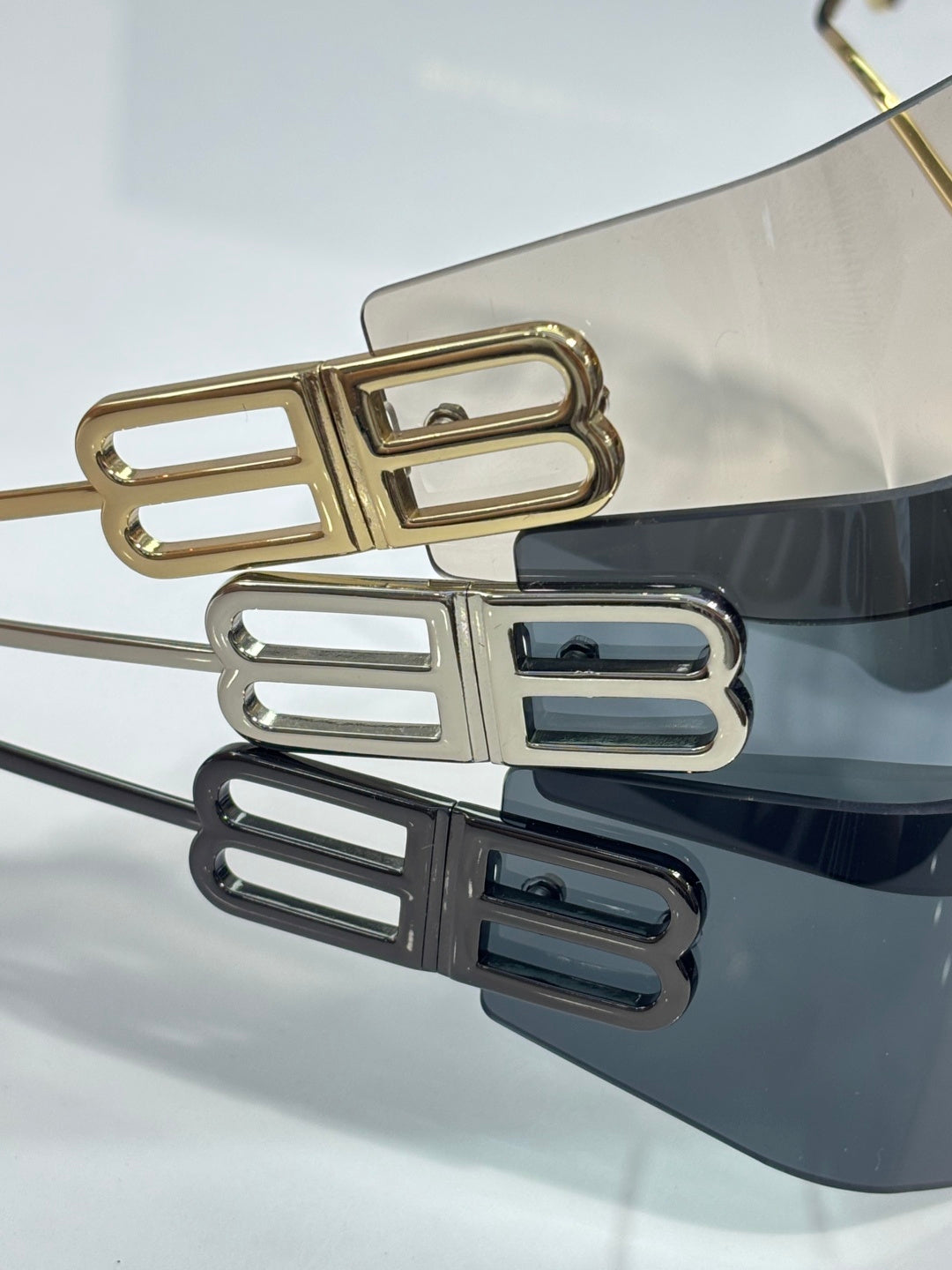 Balenciaga sunglasses close-up of stacked gold and dark logo bar on front frame