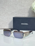 Chanel sunglasses with dark blue lenses, silver frame, gold patterned temple tips