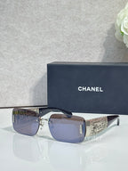 Chanel sunglasses with dark blue lenses, silver frame, gold patterned temple tips