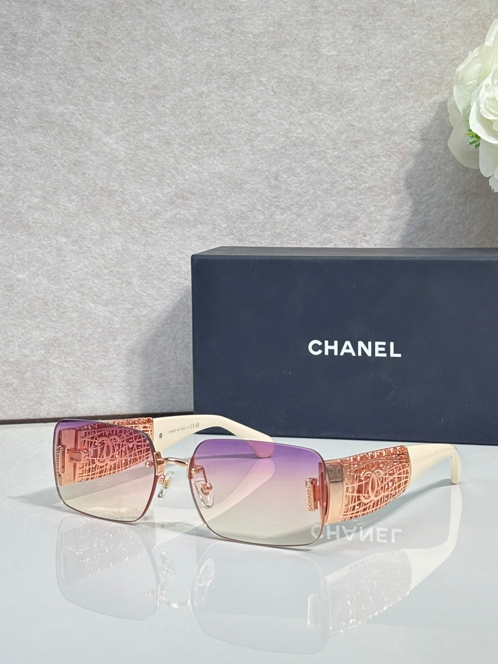 Chanel sunglasses with pink lenses, rose-gold frame, orange patterned temple tips